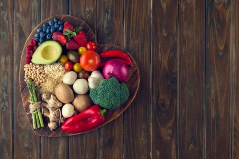 A heart shaped bowl holding foods for improving heart health